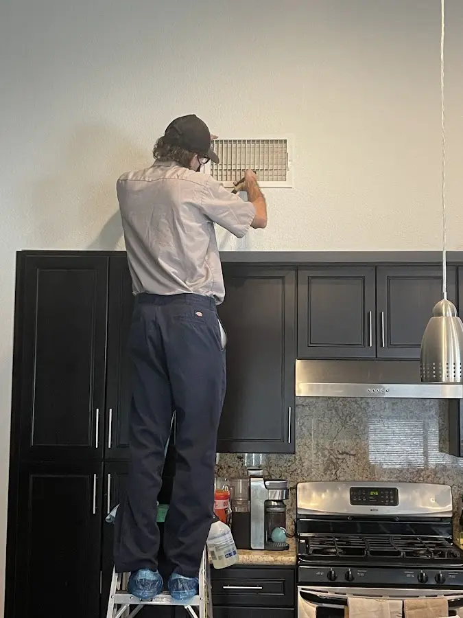 Technician inspecting an air vent during HVAC service in Greendale